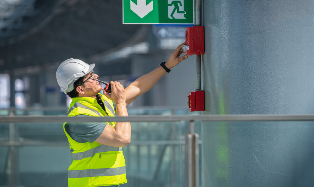 Fire safety engineer inspecting a fire alarm and emergency system